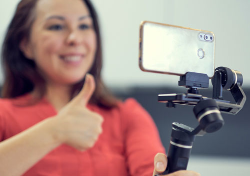 woman showing thumbs up to phone on selfie stick